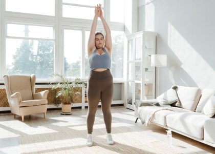 A woman practices stretching exercises in a sunlit living room, promoting wellness and healthy lifestyle.